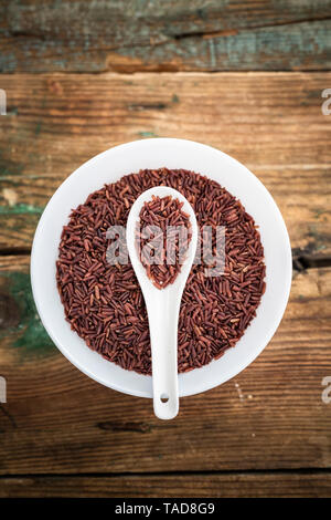 Uncooked Red rice in a bowl with a wooden spoon Stock Photo - Alamy