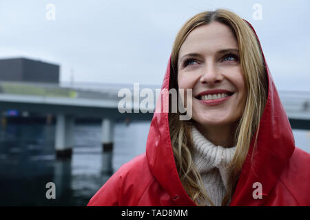 Denmark, Copenhagen, portrait of happy woman at the waterfront in rainy weather Stock Photo