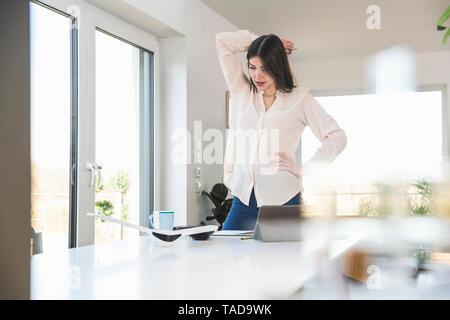 Young woman standing at table at home looking at plane model Stock Photo