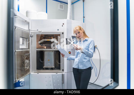 Woman holding paper and workpiece at 3d printer Stock Photo