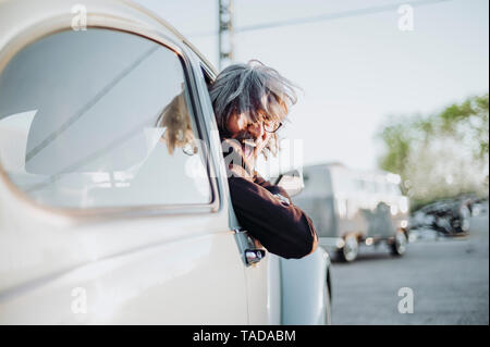 Senior man leaning out of window of vintage car screaming Stock Photo