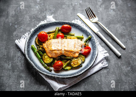 Coalfish fillet on zucchini, green asparagus and tomato, low carb Stock Photo