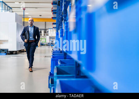 Businessman with folder walking in factory Stock Photo
