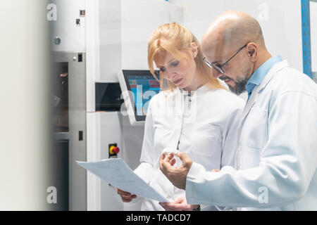 Two technicians wearing lab coats looking at plan Stock Photo