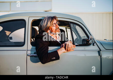 Senior man leaning out of window of vintage car Stock Photo