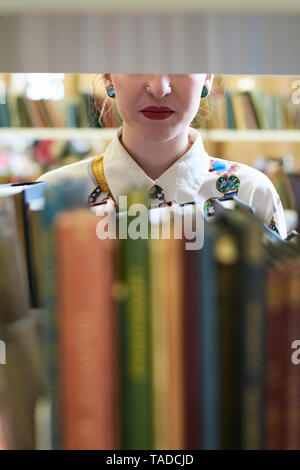 Female student in a public library, red lips Stock Photo