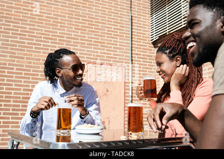 Three happy friends drinking beer at an outdoor bar Stock Photo