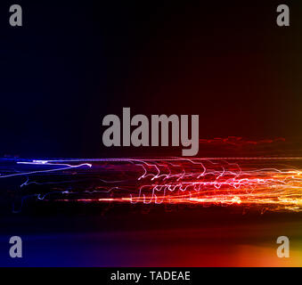 Different light trails of multicolored street lanterns and passing cars scattering in the dark, long exposure urban abstract background Stock Photo