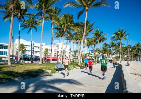 MIAMI - DECEMBER 27, 2017: Morning joggers and pedestrians share the beachfront boardwalk promenade at Lummus Park in South Beach. Stock Photo