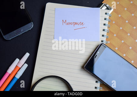 menopause written on paper isolated on black table Stock Photo