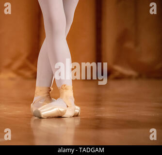 Little ballerina.Children's feet in Pointe shoes on the floor of the dance hall. Stock Photo