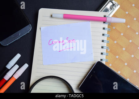 Coming Soon written on paper isolated on black table Stock Photo