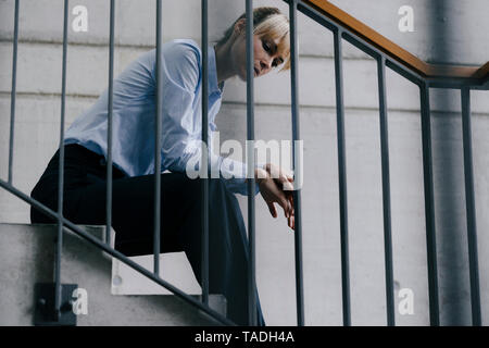Exhausted businesswoman sitting on stairs Stock Photo
