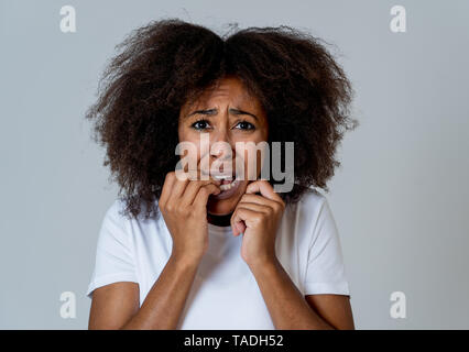 Portrait of young african american woman feeling scared and shocked making fear, anxiety gestures. Looking terrified covering herself. Copy space. In  Stock Photo