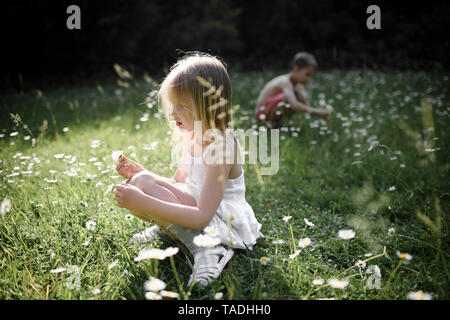 Two children picking flowers in field Stock Photo