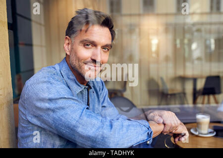 Portrait of confident man behind windowpane in a cafe Stock Photo