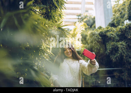 Happy young woman taking a selfie in a park Stock Photo