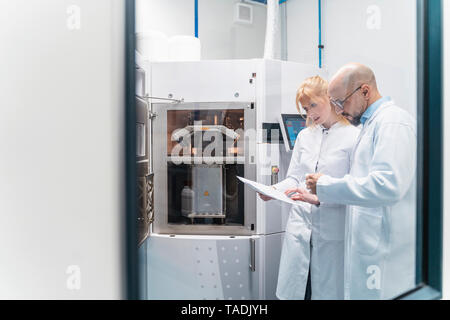 Two technicians wearing lab coats looking at plan Stock Photo