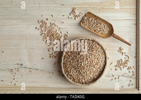 Organic spelt wheat in bast bowl, on wood, from above Stock Photo