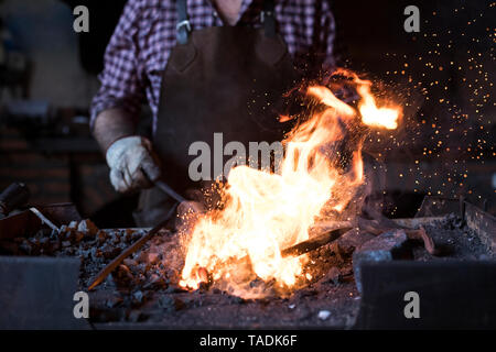 Close-up of blacksmith working at forge in his workshop Stock Photo