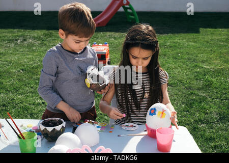 Friends painting Easter eggs in garden Stock Photo