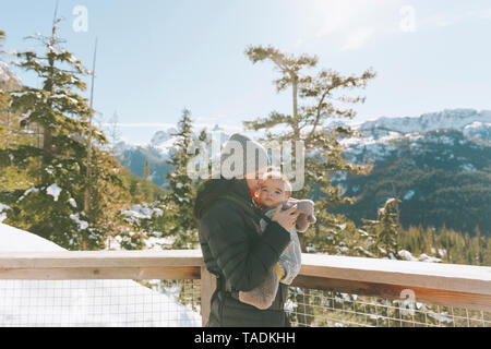 Mother holding her baby son on an observation deck, looking over Squamish, Canada