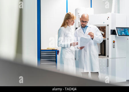 Two technicians wearing lab coats looking at plan Stock Photo