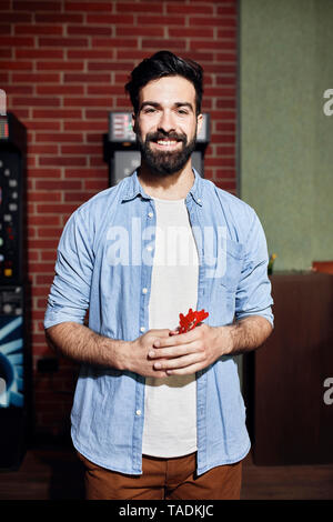 Portrait of smiling man holding darts Stock Photo