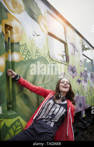 Portrait of happy teenage girl at a painted train car