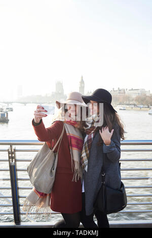 UK, London, two women taking a selfie on Millennium Bridge with cityscape in background Stock Photo