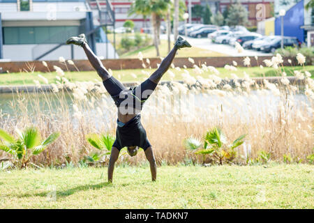 Man in black sportswear doing handstand on a meadow Stock Photo