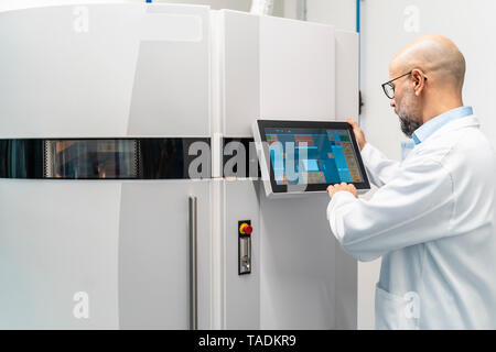 Technician wearing lab coat operating 3d printer Stock Photo