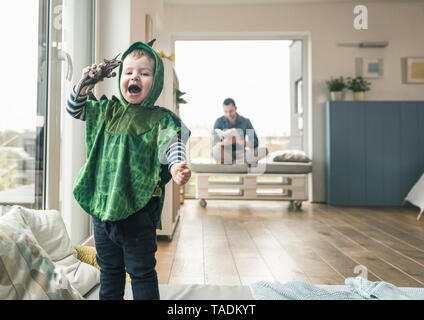 Happy boy in a costume playing with toy figure at home Stock Photo