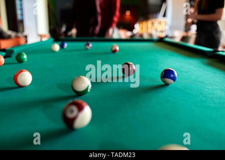 Billiard balls on table with people in background Stock Photo