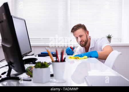 Janitor cleaning white desk in modern office Stock Photo