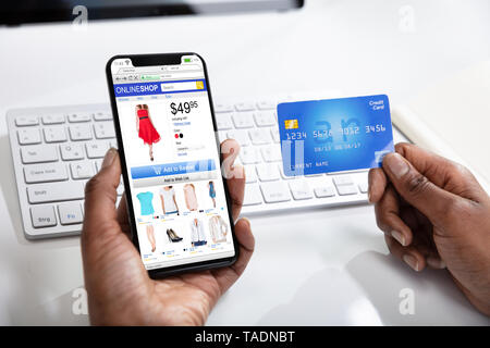 A Woman Doing Online Shopping Using Cell Phone And Credit Card Stock Photo