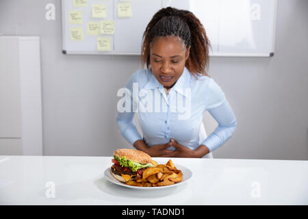 Young Woman Suffering From Stomach Pain While Having Breakfast