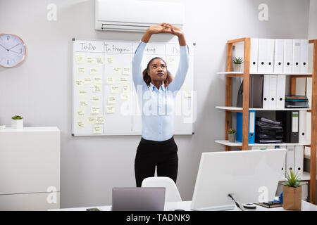 Young Businesswoman Stretching Her Arms In Office Stock Photo