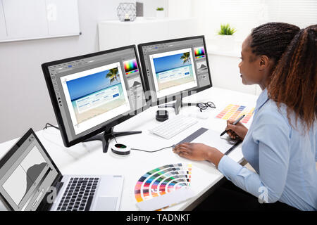 Young Female Designer Editing Photos On Computer In Office Stock Photo