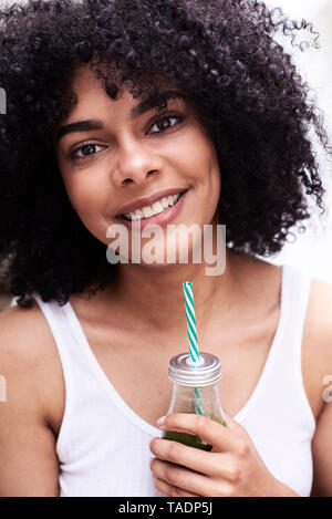 Portrait of smiling beautiful young woman holding green healthy smoothie Stock Photo
