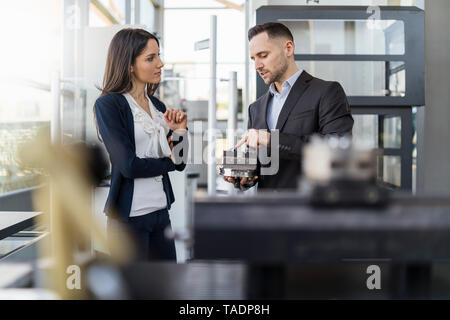 Businessman and businesswoman examining workpiece in factory Stock Photo