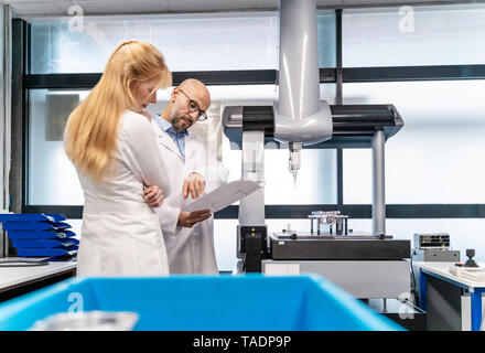 Two technicians wearing lab coats looking at plan Stock Photo