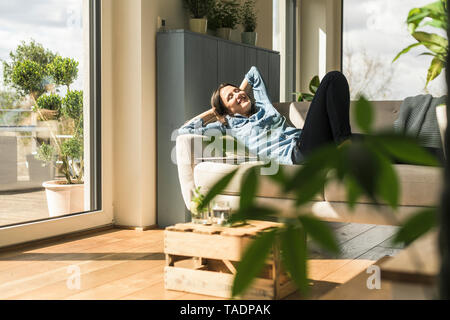 Happy woman lying on the couch at home Stock Photo