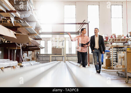 Two men walking in factory warehouse Stock Photo