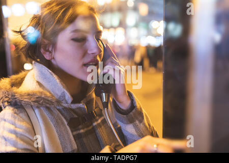 Spain, Madrid, young woman in the city using a phone box Stock Photo