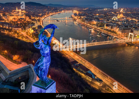 Budapest, Hungary - Blue illuminated Hungarian statue of liberty on World Autism Awareness Day with skyline of Budapest at background at dusk Stock Photo