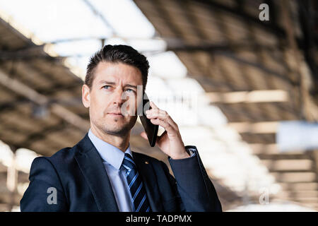 Businessman on cell phone at train station Stock Photo