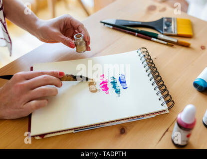 Woman's hand applying colour pigments on colouring book Stock Photo