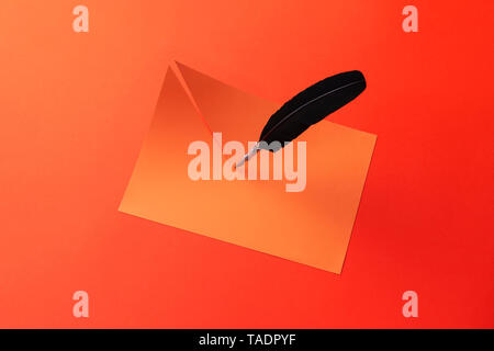 Quill pen cut the paper in half over red background Stock Photo