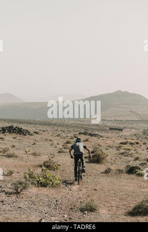 Spain, Lanzarote, mountainbiker on a trip in desertic landscape